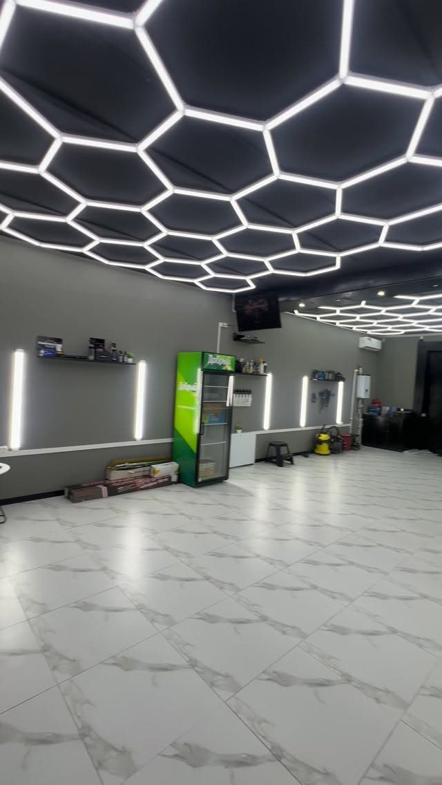 A modern empty garage with a black honeycomb LED ceiling and white tiled flooring.