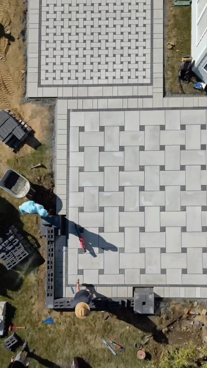 Light grey paving stones laid in a basket weave pattern during patio construction.