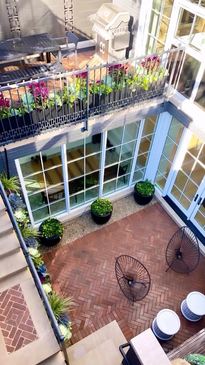 Reddish-brown bricks laid in a herringbone pattern on a courtyard patio with chairs and plants.