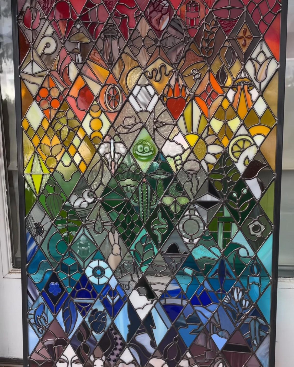 Colorful Stained Glass Design: 10 Ideas to Light a Room 1 Colorful stained glass panel with diamond-shaped pieces in a vibrant color gradient.