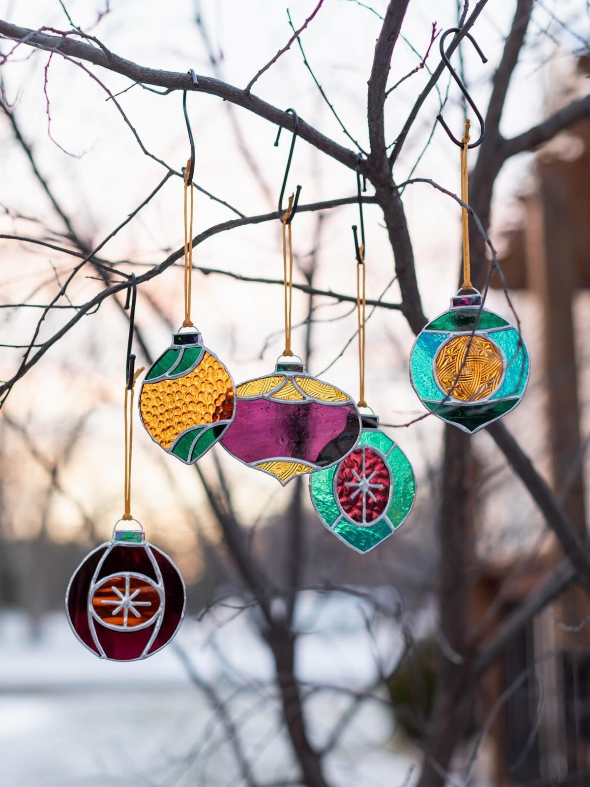 Colorful Stained Glass Design: 10 Ideas to Light a Room 5 Five colorful stained glass ornaments hanging from the branches of a bare tree outdoors.