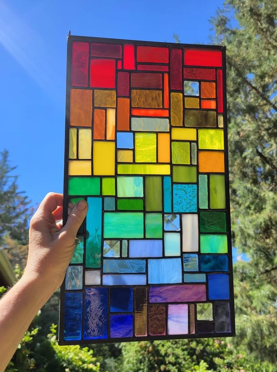 Colorful Stained Glass Design: 10 Ideas to Light a Room 9 A rectangular stained glass panel with vertical color gradients held up against a blue sky.