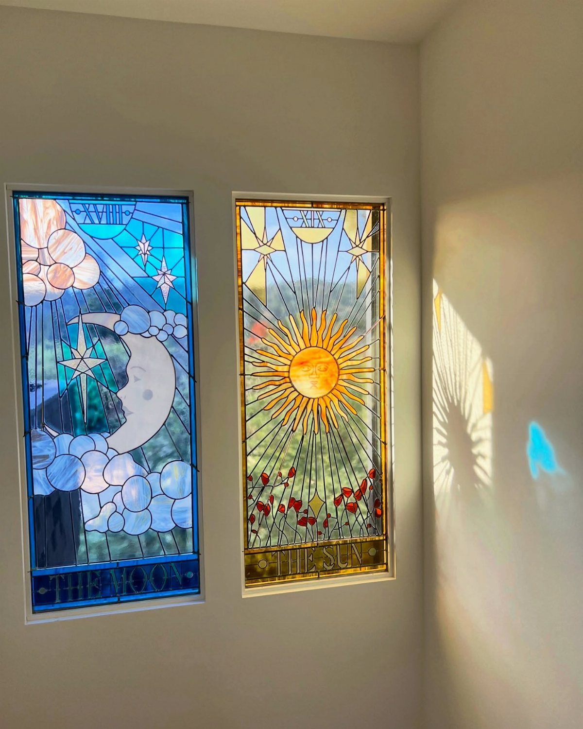 Colorful Stained Glass Design: 10 Ideas to Light a Room 2 Two stained glass panels depicting the moon and the sun mounted on a white wall.