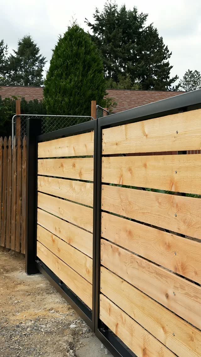 Modern horizontal wood slat fence with a black metal frame in a yard.