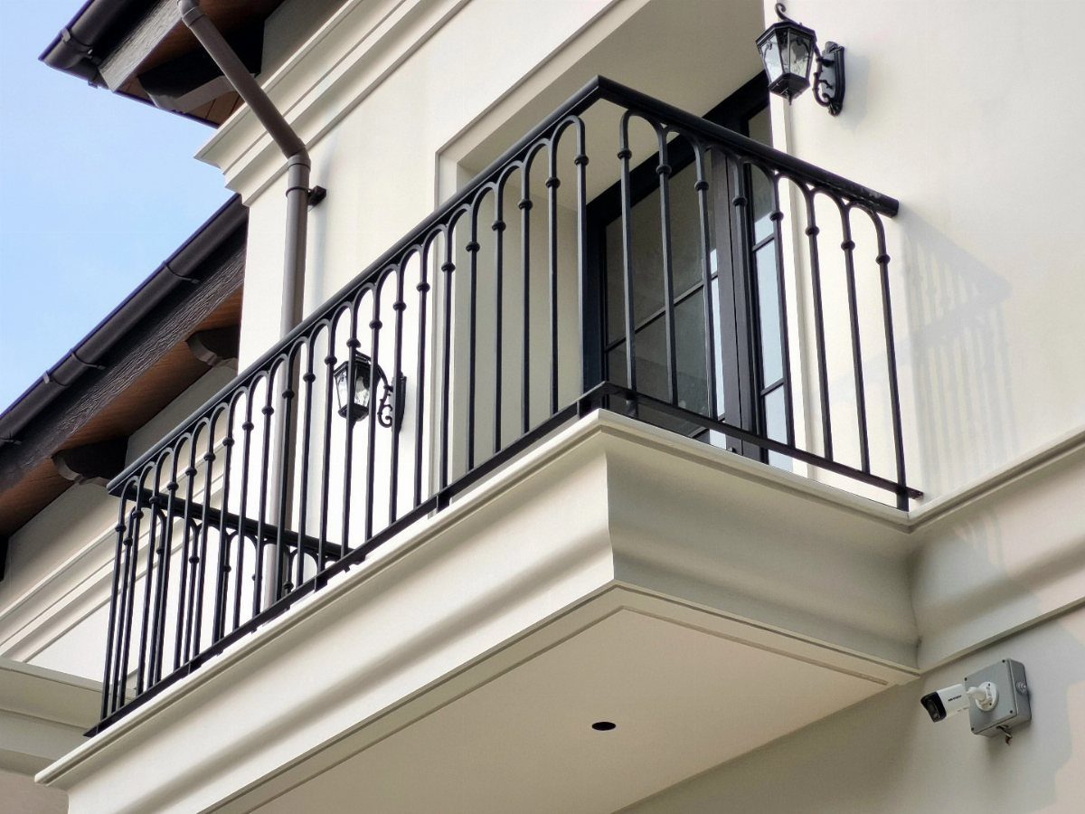 Black wrought iron railing installed on a white balcony of a modern house.