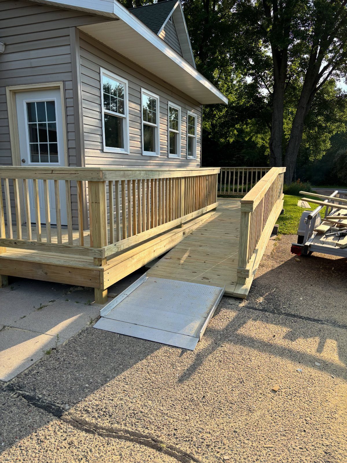 A wooden deck ramp with metal non-slip plating leading from a house to a driveway.