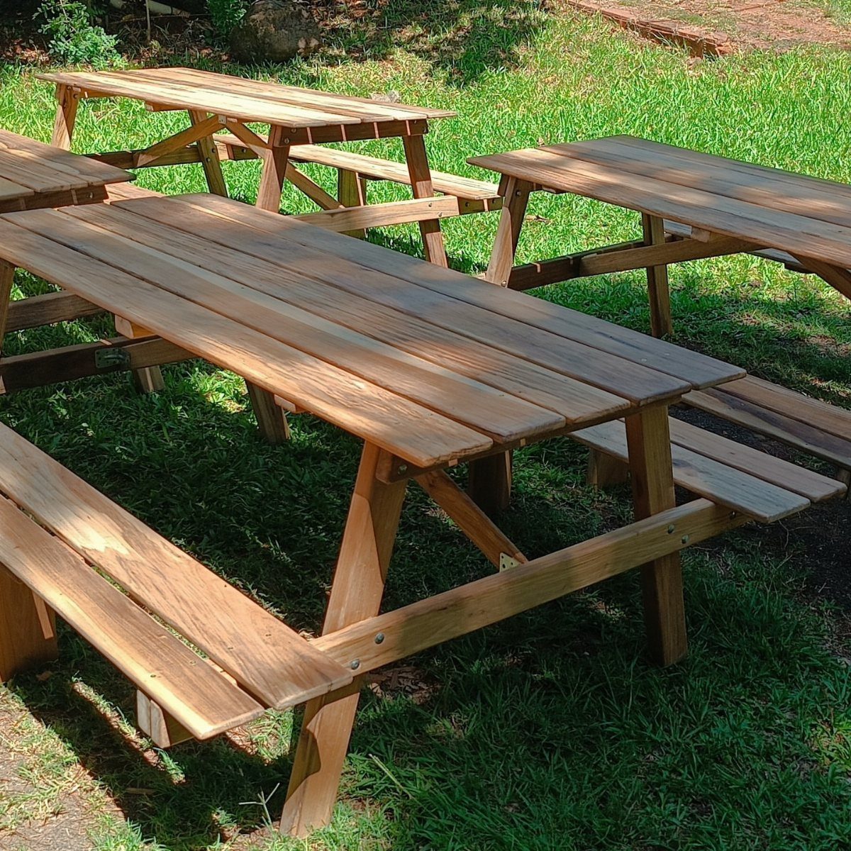 Easy Patio Table DIY: 8 Projects for Your Yard 3 Wooden picnic tables with attached benches sitting on a green grass lawn outdoors.
