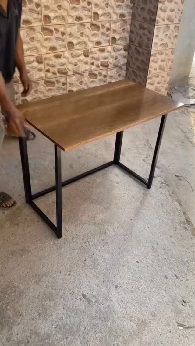 Easy Patio Table DIY: 8 Projects for Your Yard 6 A rectangular wooden table with a black metal frame standing on a concrete floor.