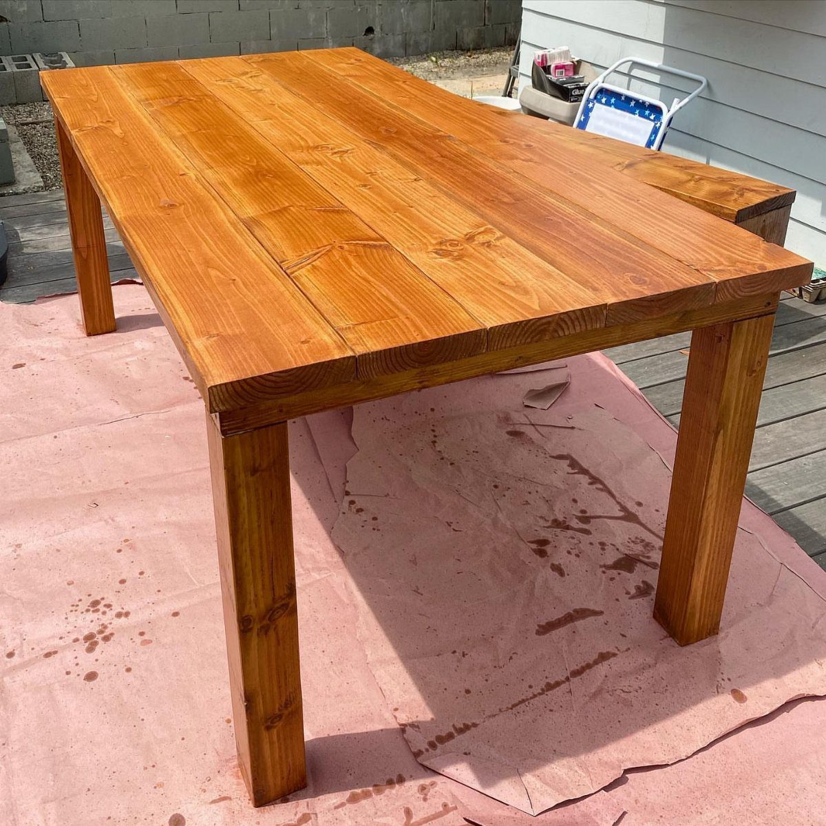 Easy Patio Table DIY: 8 Projects for Your Yard 1 A simple rectangular wooden outdoor dining table resting on a pink drop cloth.