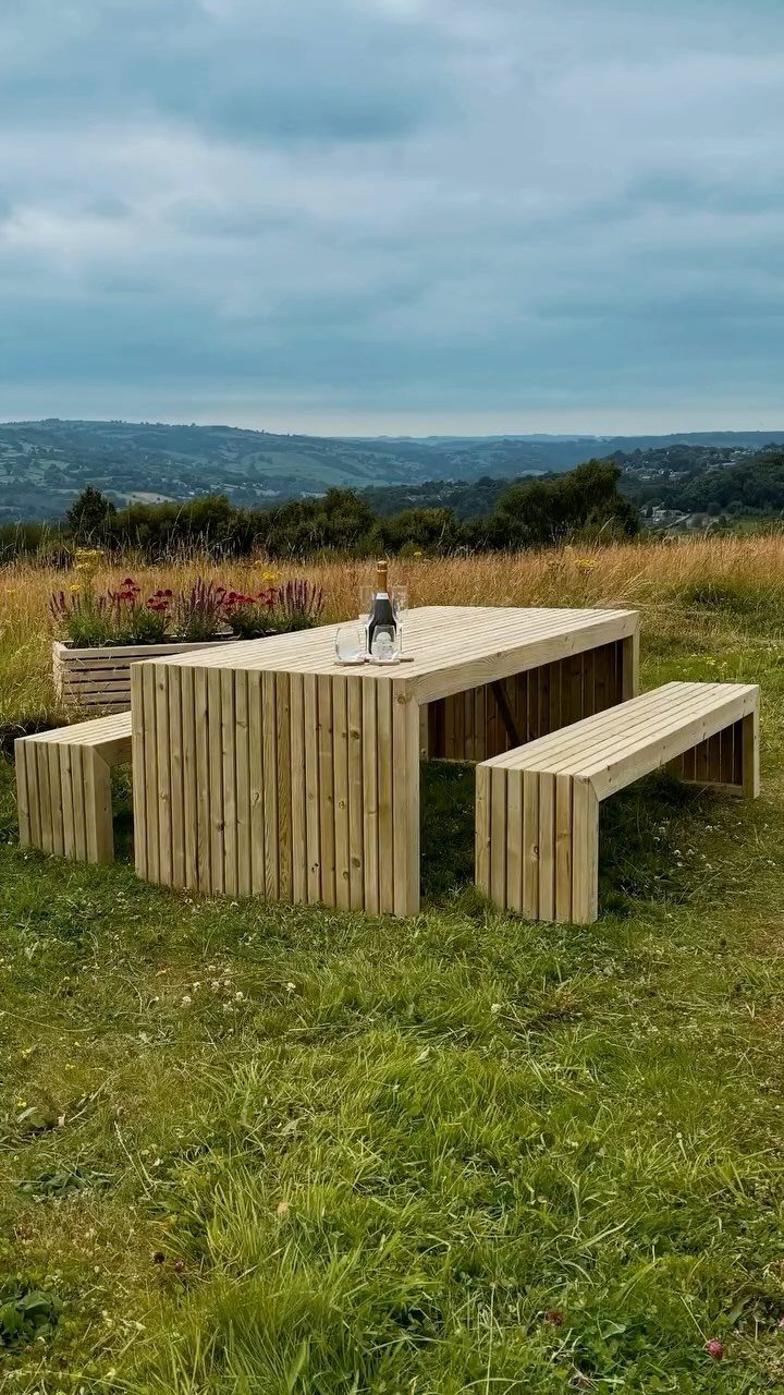 Easy Patio Table DIY: 8 Projects for Your Yard 2 A light wood slatted outdoor dining table and two matching benches on a grassy hill.