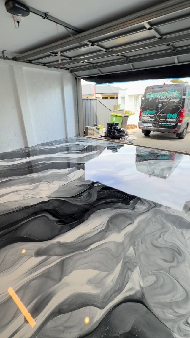 Swirling black and grey marble pattern epoxy coating on a shiny garage floor.