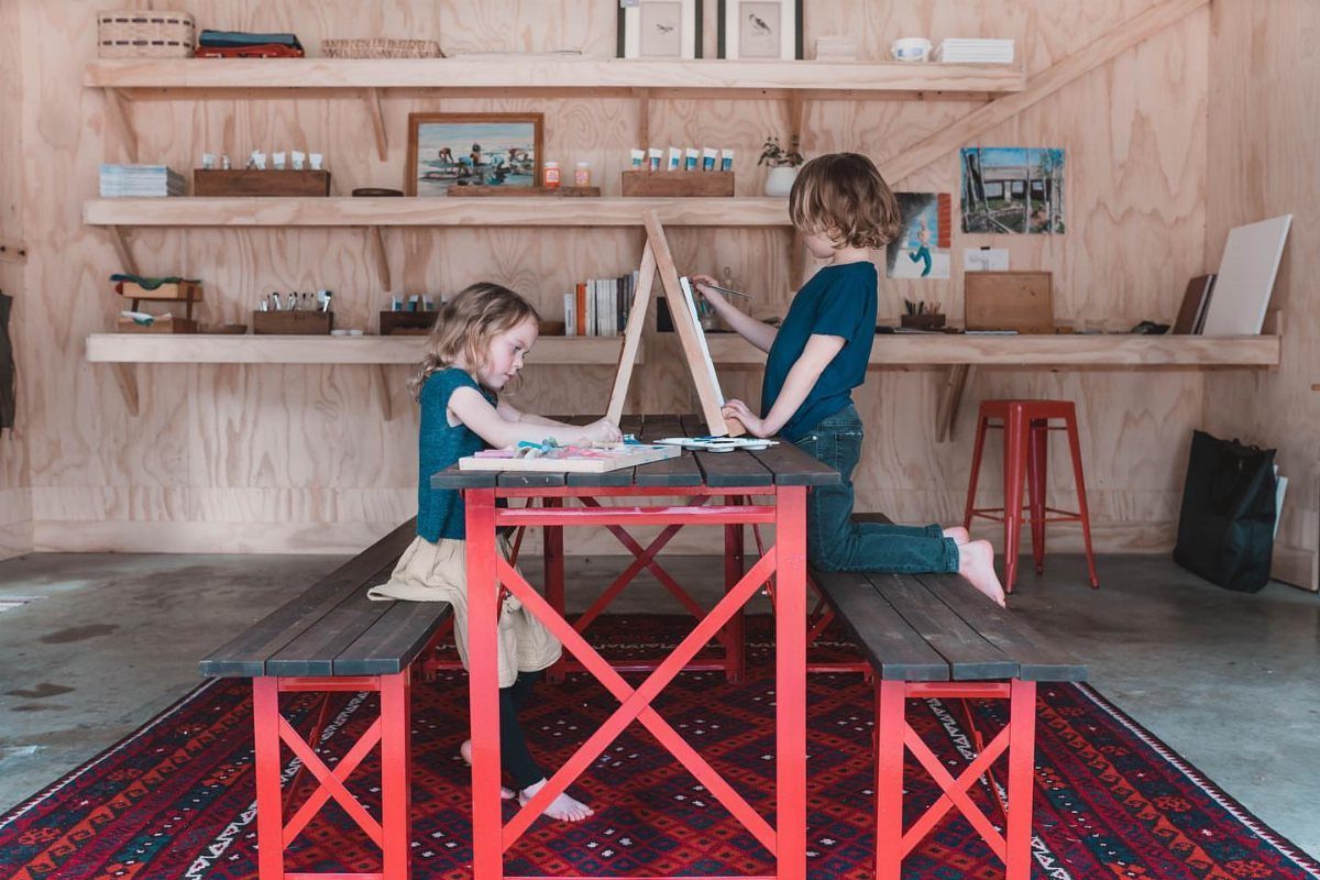 Garage to Family Room Conversion: 9 Ideas for 2026 4 Two children sitting at a red table working on art projects in a wooden room.