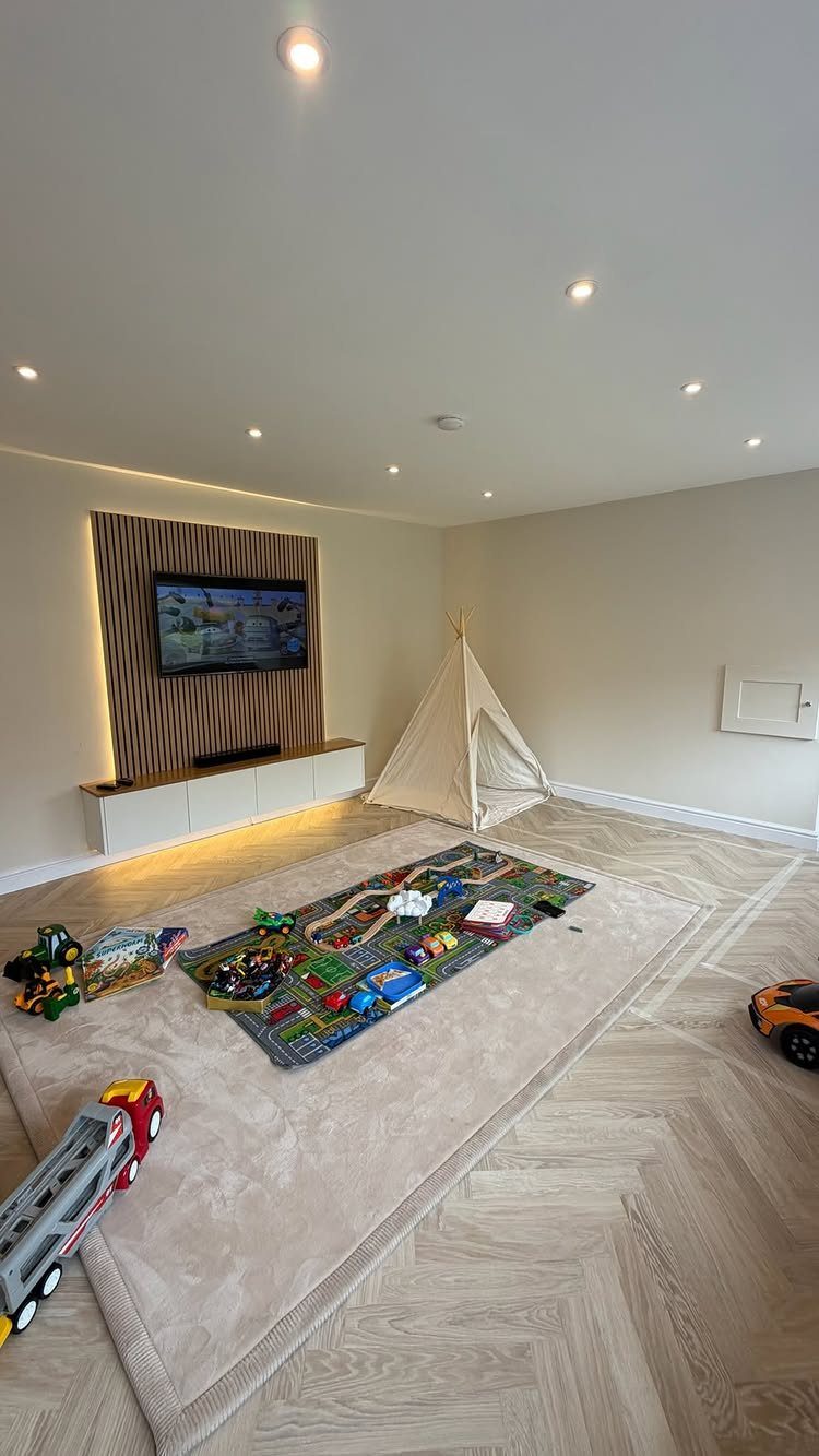 Garage to Family Room Conversion: 9 Ideas for 2026 8 Modern living room with a wood-slat TV wall, white media console, play tent, and toys on a rug.