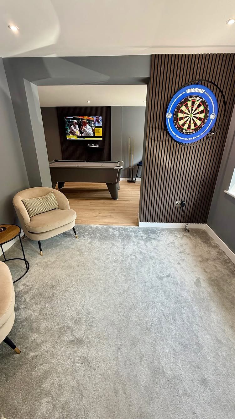 Garage to Family Room Conversion: 9 Ideas for 2026 9 A converted living space featuring a lounge area, a pool table, and a dartboard on a slatted wall.