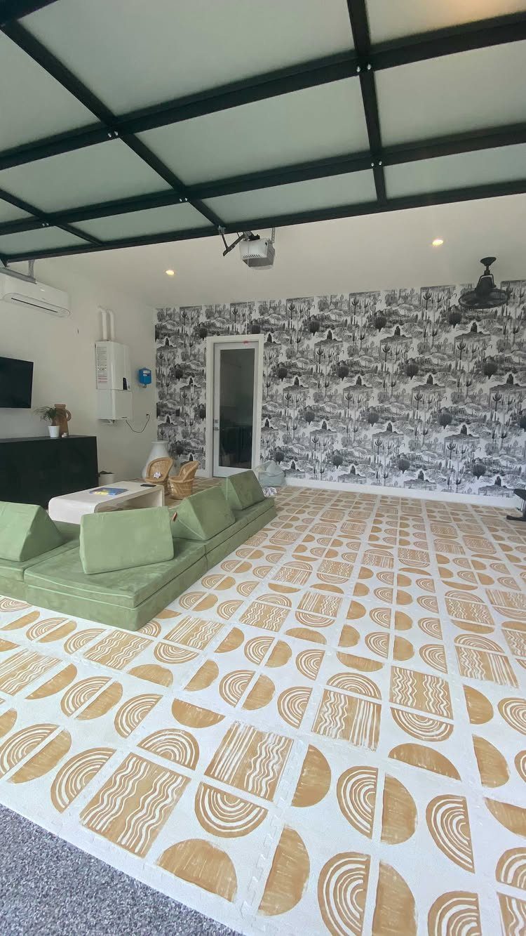 Garage to Family Room Conversion: 9 Ideas for 2026 6 A modern living room with a green sectional sofa and patterned mustard yellow rug.