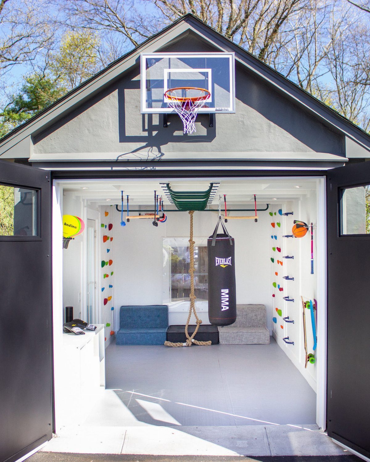 Garage to Family Room Conversion: 9 Ideas for 2026 2 A converted garage space featuring climbing walls, a punching bag, and a basketball hoop.
