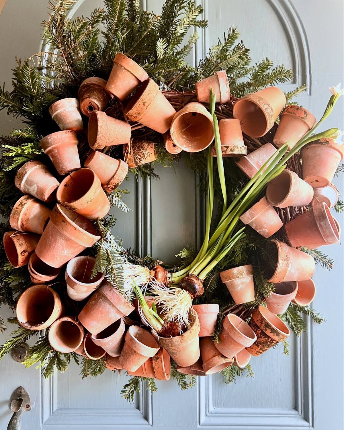 21 Home Decor Ideas for Garden Spaces That Work in Any Yard 5 Terracotta clay pots arranged in a circular wreath shape with green evergreen foliage.