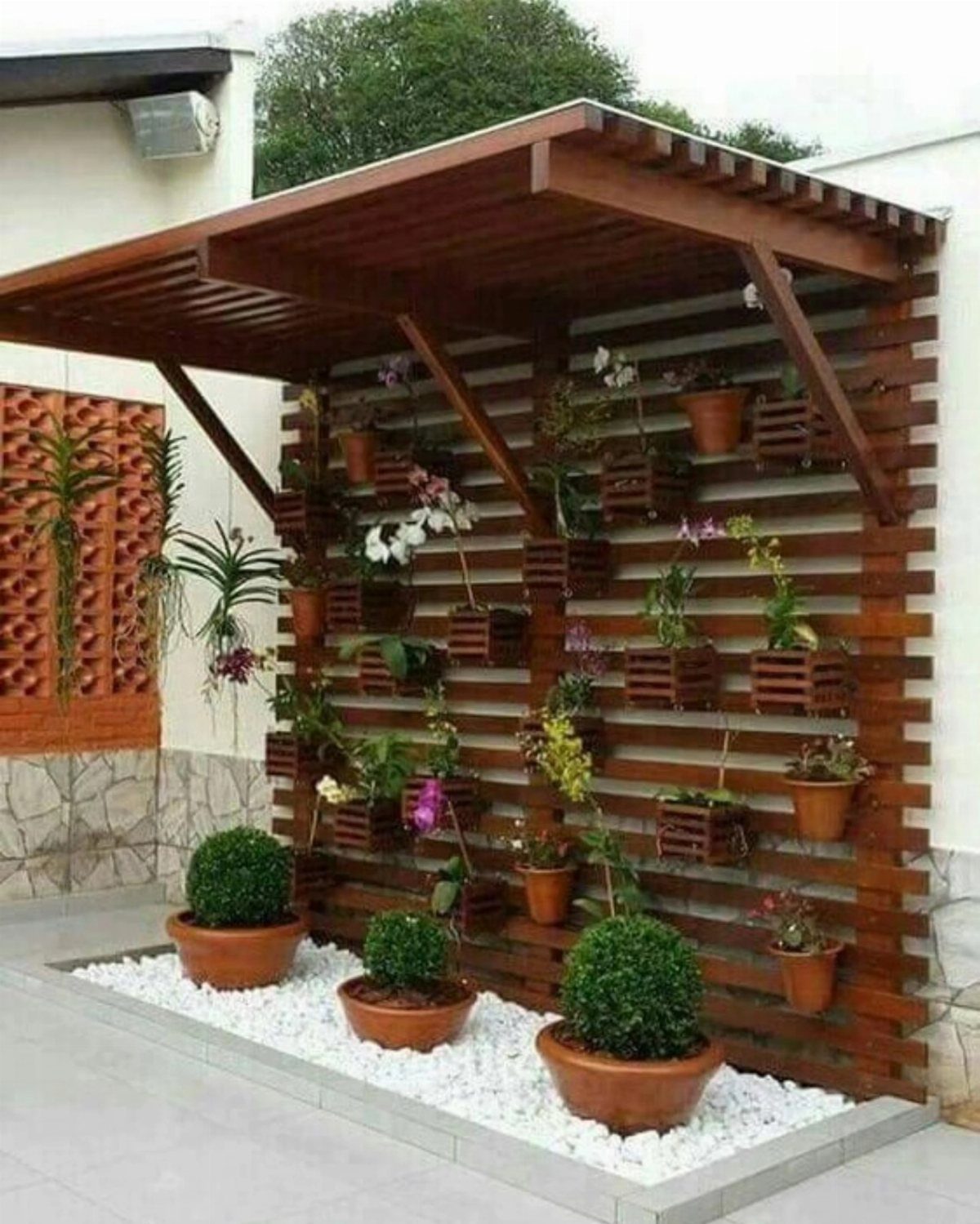 21 Home Decor Ideas for Garden Spaces That Work in Any Yard 16 A wooden slat wall structure acting as a vertical garden with small wooden crates holding various plants.