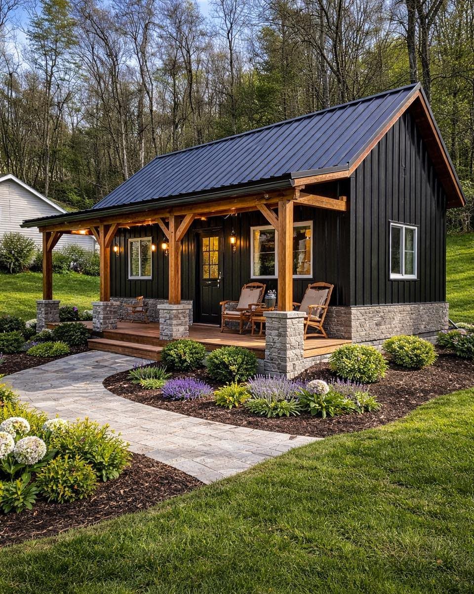 9 Modern Farmhouse Shed Ideas for 2026 4 Black farmhouse shed with a covered wooden porch, stone pillars, and a landscaped garden walkway.