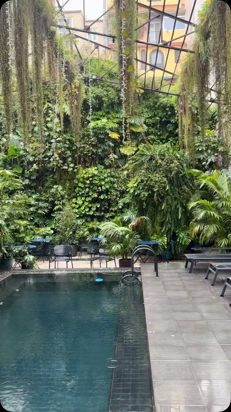 Pool Deck Ideas: 20 Designs From Breeze Blocks to Mountain Views 8 Lush tropical pool area with dense vertical gardens and hanging vines over a stone deck.
