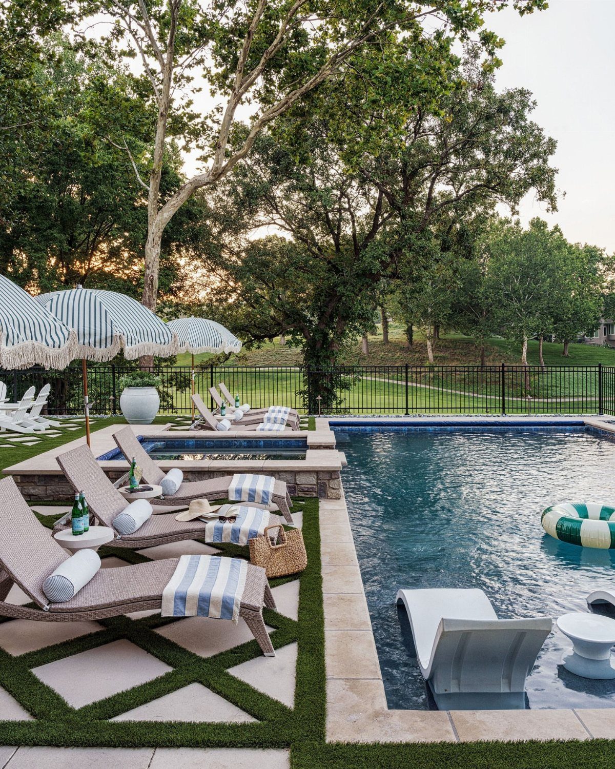 Pool Deck Ideas: 20 Designs From Breeze Blocks to Mountain Views 9 Lounge chairs with striped towels sit on a stone and grass pool deck.