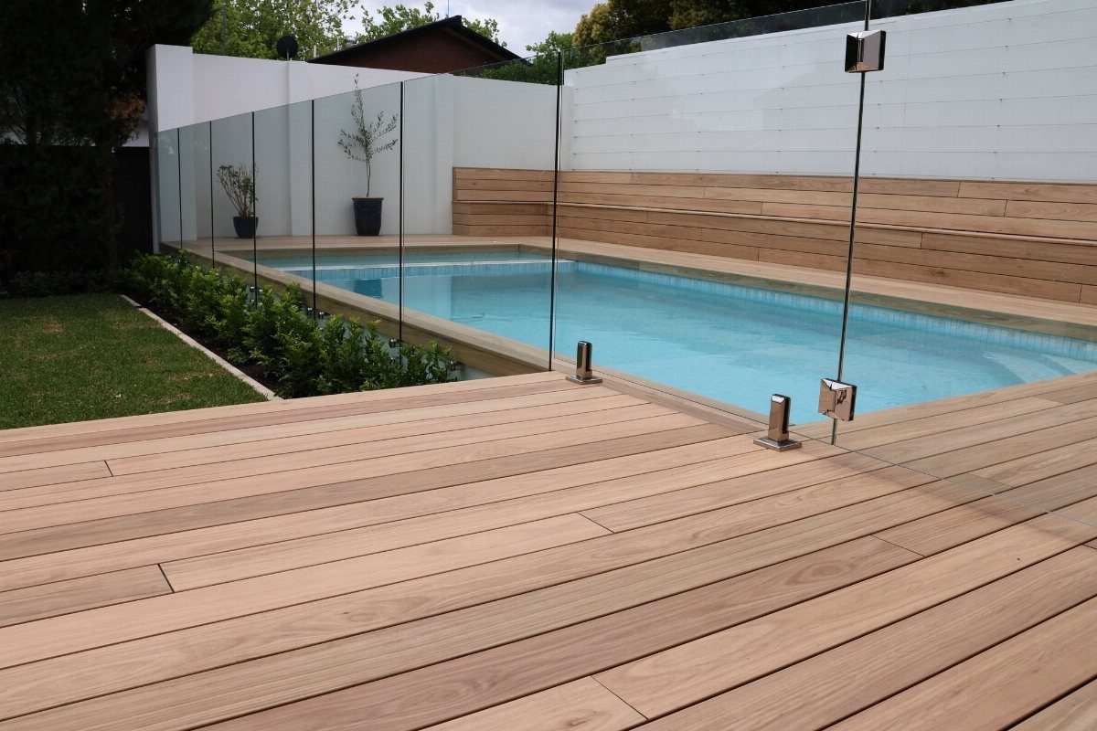 Pool Deck Ideas: 20 Designs From Breeze Blocks to Mountain Views 12 Light wood decking surrounds a rectangular swimming pool enclosed by a glass safety fence.