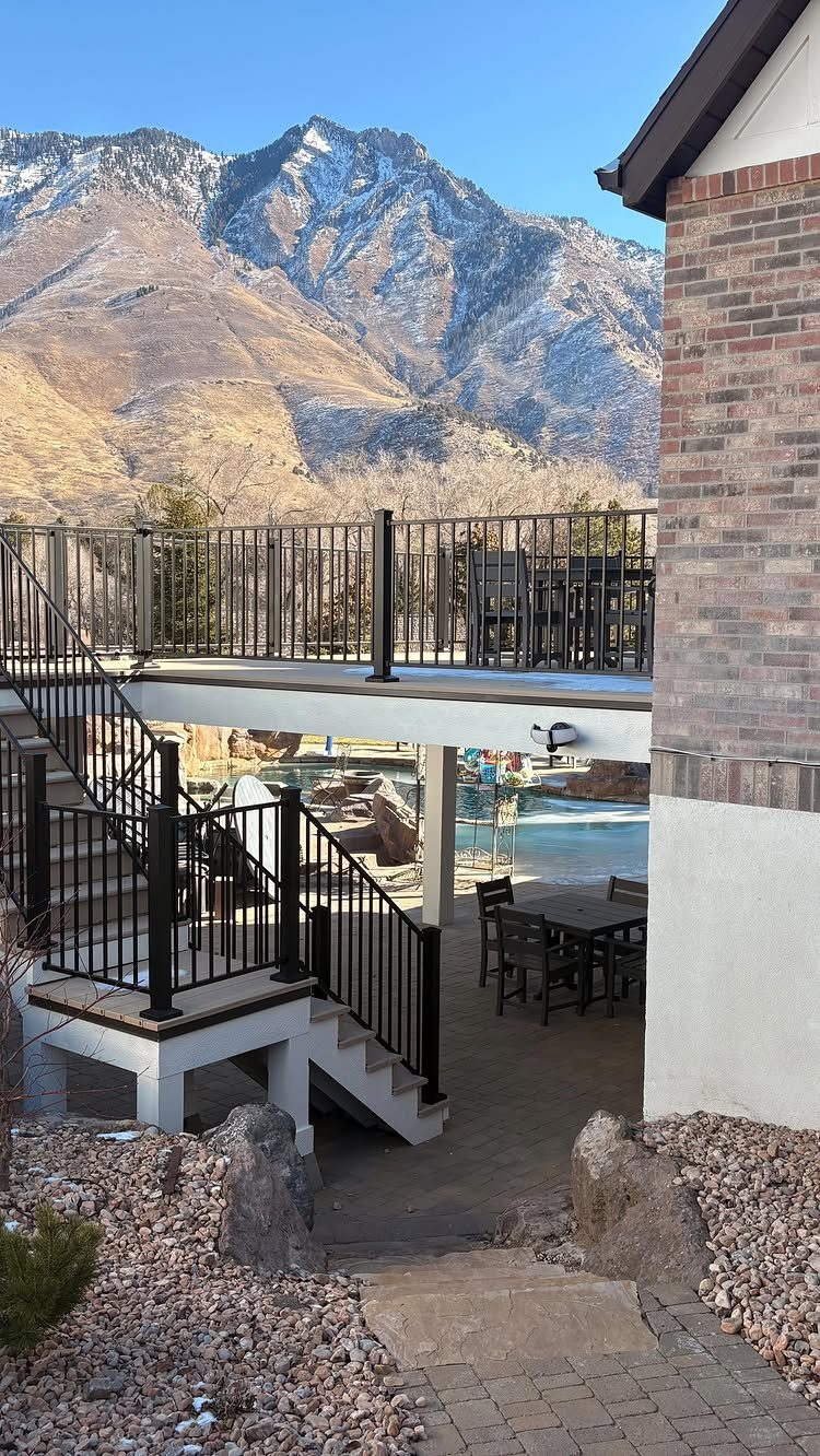 Pool Deck Ideas: 20 Designs From Breeze Blocks to Mountain Views 20 Multi-level outdoor patio and deck with black railings overlooking a pool and snowy mountains.