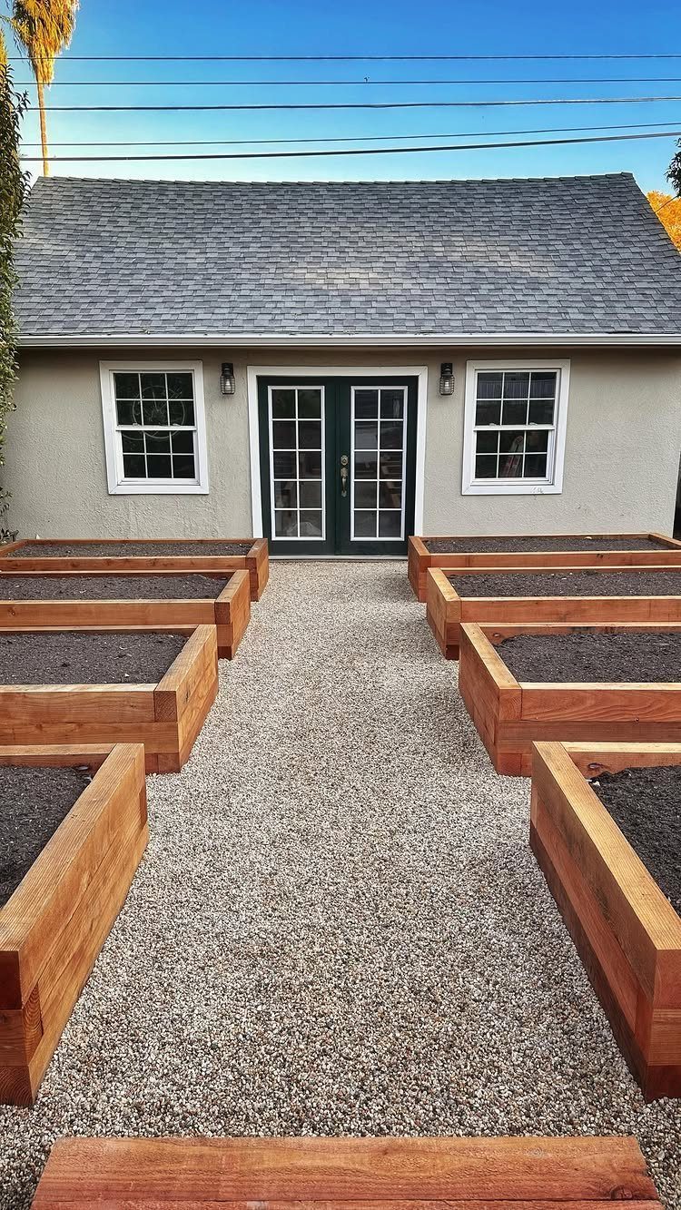 Raised Garden Beds: 9 Ideas for Materials, Layout and Drainage 6 Wooden raised garden beds filled with dark soil arranged on a gravel path in a backyard.