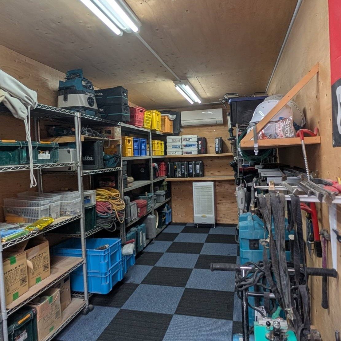 Metal shelving units filled with toolboxes and blue plastic bins in an organized tool shed.