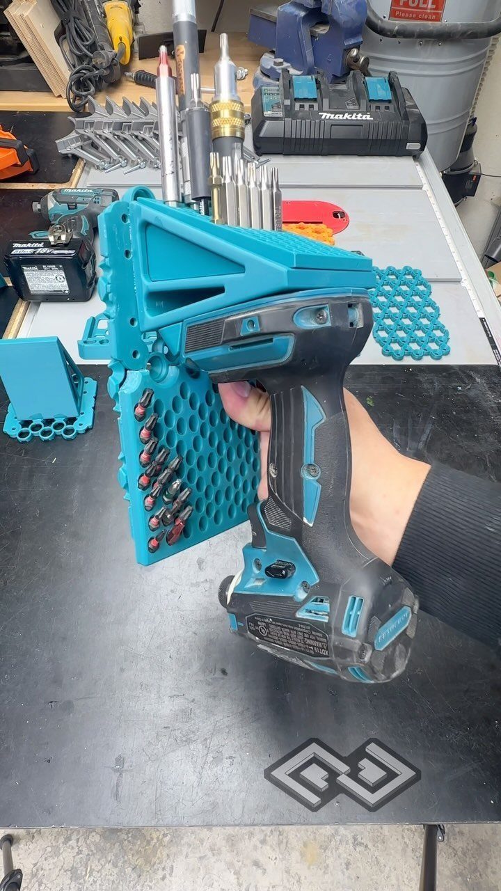 A person holding a teal 3D-printed custom tool holder designed for a cordless drill.