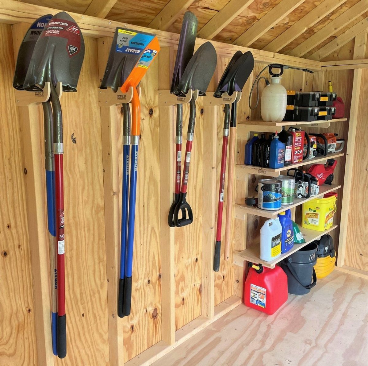 Garden tools like shovels hang on wooden wall hooks next to shelves filled with supplies.