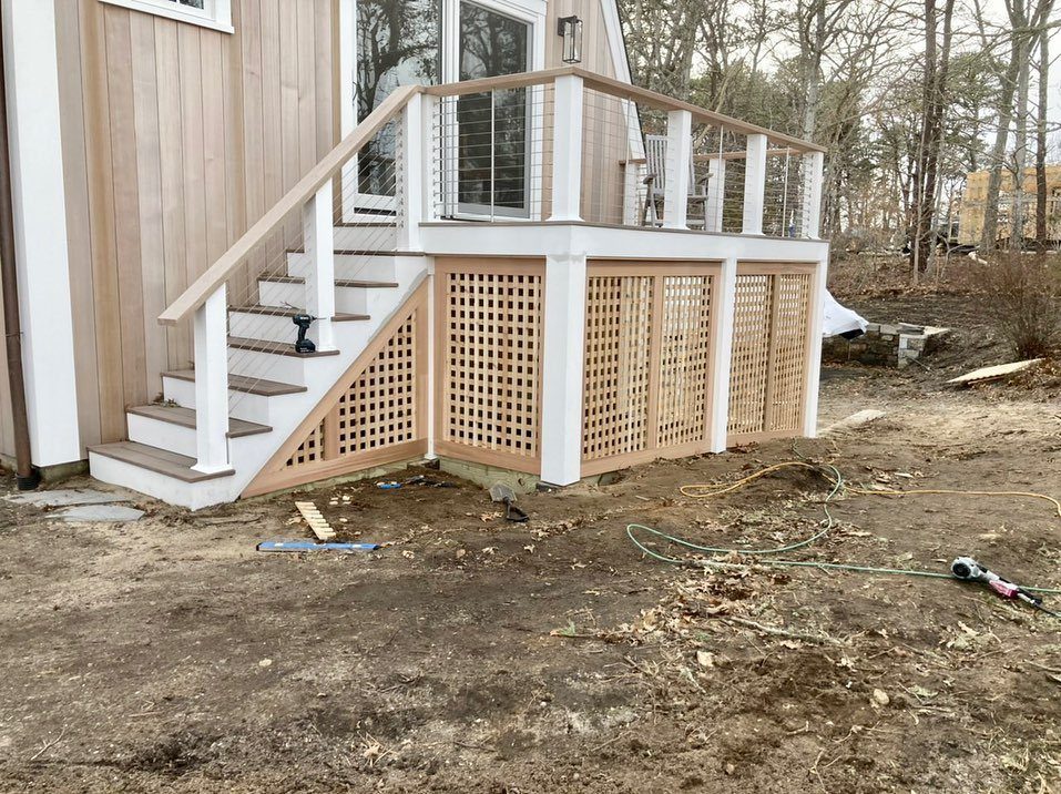 A newly constructed wooden deck with white railings and tan lattice panels underneath.
